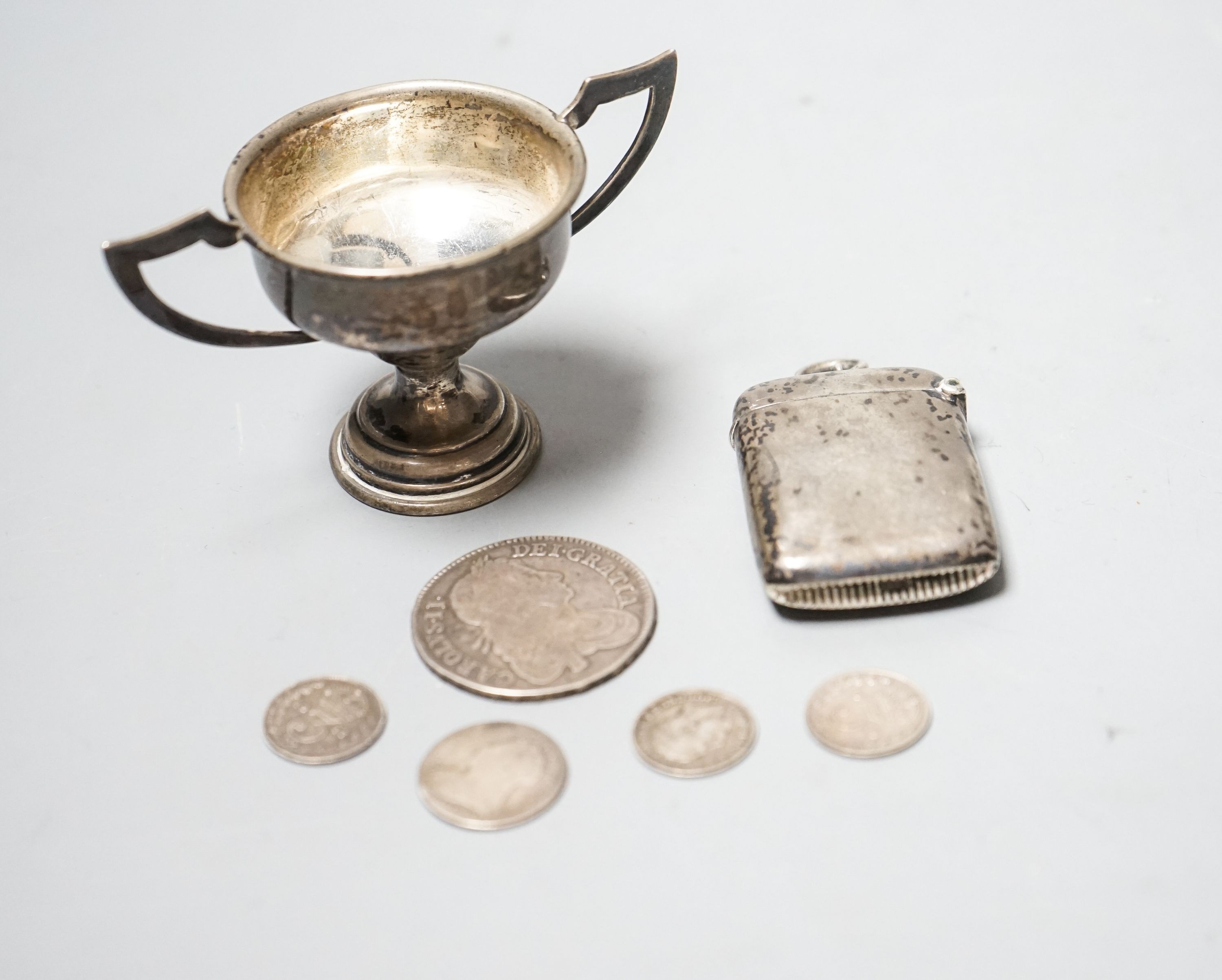 A silver vesta case, a small silver trophy cup and five assorted coins including a Charles II half crown, 1664.